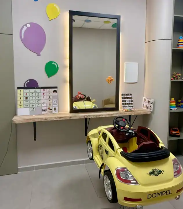Sala sensorial exclusiva para atendimento TEA, com cadeira em formato de carrinho e prancha de comunicação